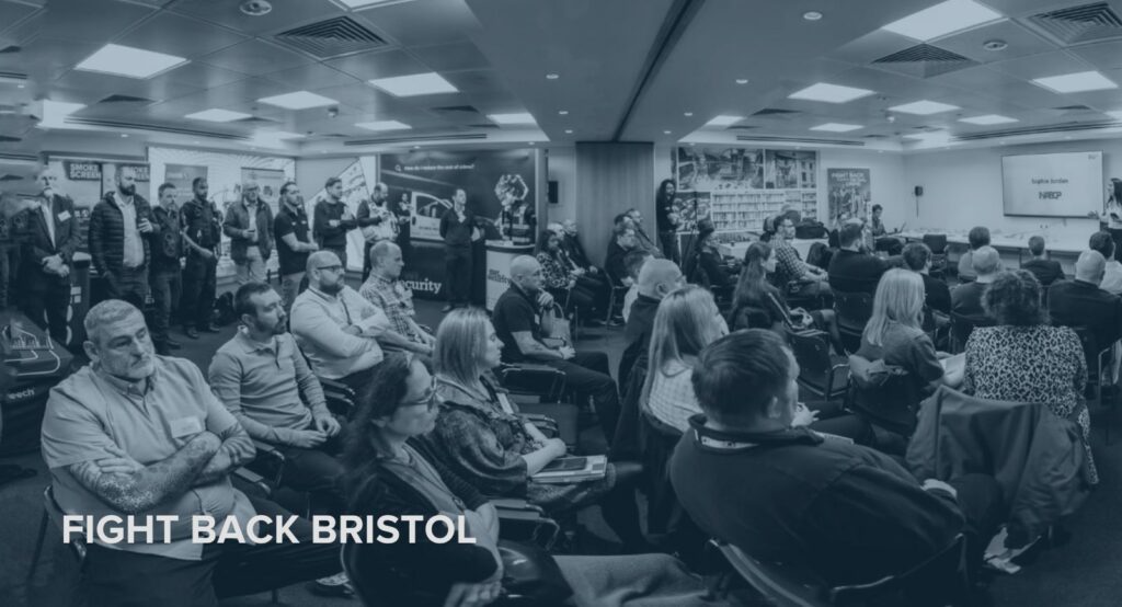 Fight Back Bristol conference session — full room of retailers and security professionals, Smoke Screen branding and Sophie Jordan presenting on behalf of NABCP