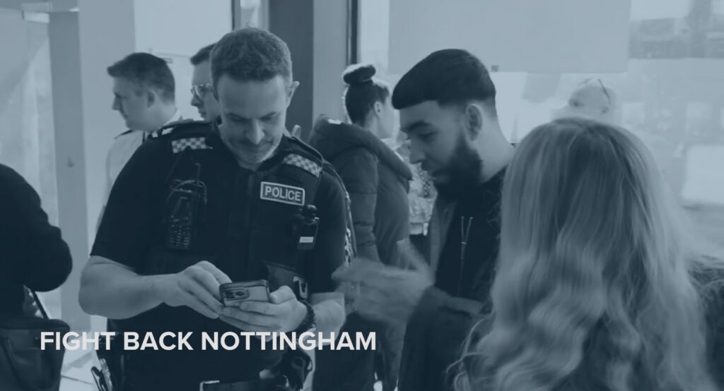 Fight Back Nottingham — police officer and retailer looking at information on a mobile phone together at the event.