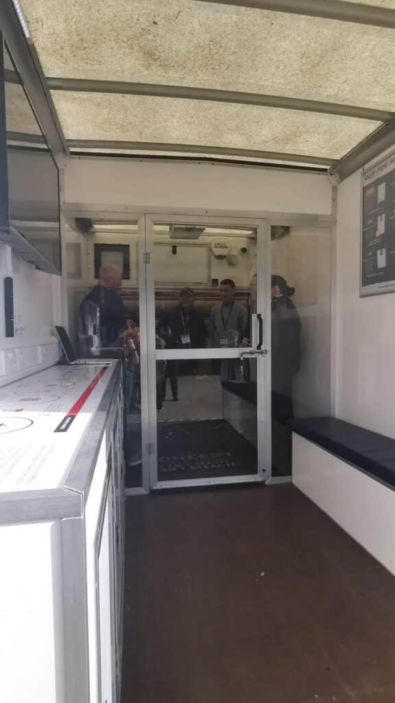 Attendees Behind The Glass Door Of The Smoke Screen Security Fog Test Chamber The Test Chamber Before The Fog: Within Seconds Of Activation, The Glass Door Disappears From View.